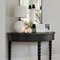 Dark finish demilune table with white lamp and picture frames. 