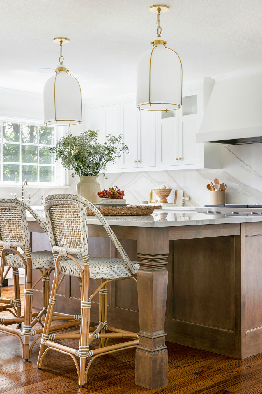 Kitchen with island featuring two large white and brass pendant lights