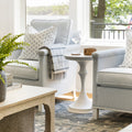 White stonecast side table between two blue striped chairs