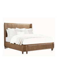A woven bed frame with a white mattress and pillows on it. The bed has a shelter design with a headboard and footboard that curve inward.
