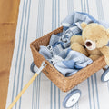 Blue and ivory striped cotton rug with children's rattan wagon