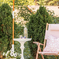 White stonecast side table next to a pink striped outdoor chair