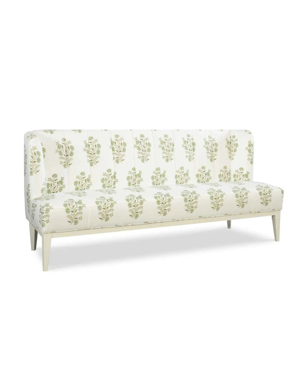 An upholstered banquette with a wood base, featuring a beige fabric with a green floral pattern.