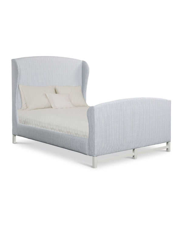An upholstered Ford Bed with Foot Board in a light color fabric, featuring a large headboard and footboard, with the bed dressed in white linens.