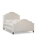A queen-sized upholstered bed with a scalloped headboard and a wooden footboard, featuring a beige fabric on the headboard and a plain wood finish on the footboard.
