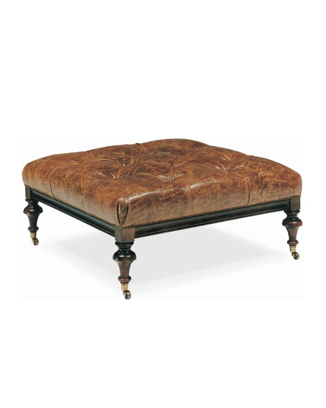 A square brown leather ottoman with tufted upholstery, featuring turned legs and casters.