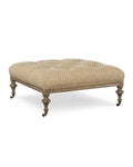 An upholstered square ottoman with a geometric pattern on the fabric, featuring wooden legs and casters.