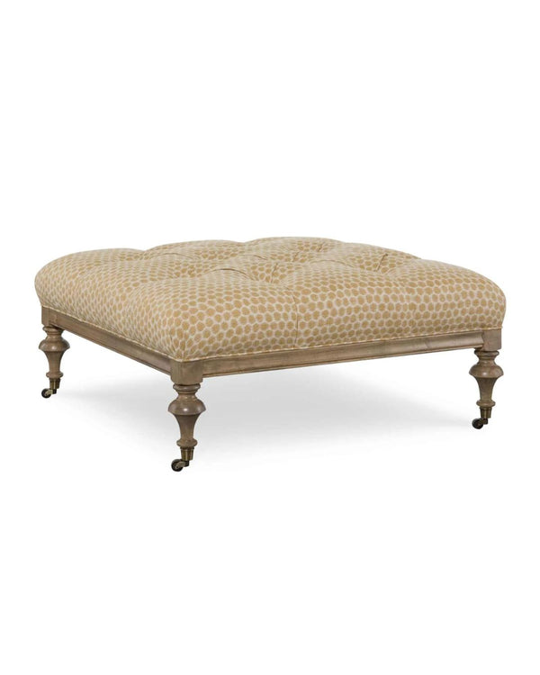 An upholstered square ottoman with a geometric pattern on the fabric, featuring wooden legs and casters.