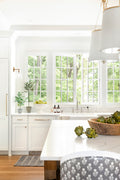 White pedestal bowl filled with pears on kitchen counter by window