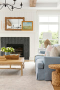 Bright living room with black fireplace and blue couch resting on beige and pale blue rug