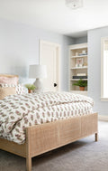Bed frame designed with a natural mango frame and woven cane inset in bedroom with floral duvet