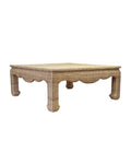 A square-shaped wicker coffee table with scalloped edges in a brown color.