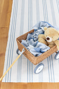 Blue and ivory striped cotton rug with children's rattan wagon