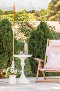 White stonecast side table next to a pink striped outdoor chair